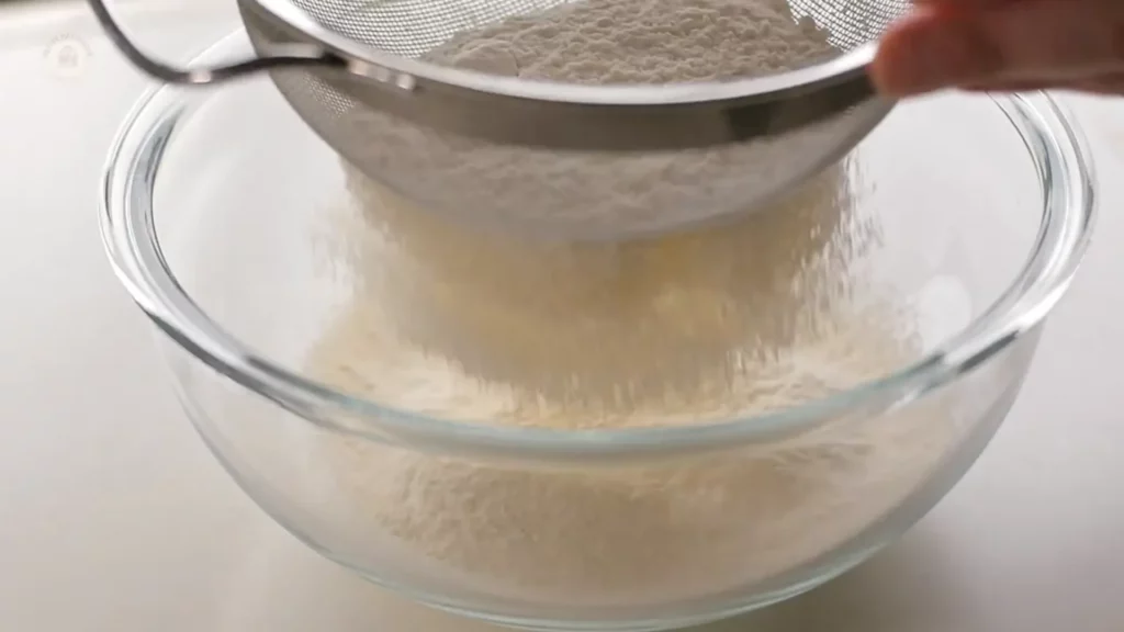 Farine tamisée dans un bol pour obtenir une pâte sans grumeaux