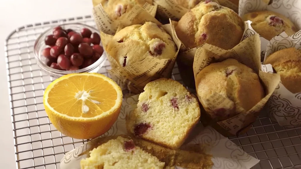 Muffins à l’orange et canneberges présentés avec une orange tranchée