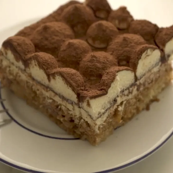 Portion de tiramisu servie sur une assiette blanche avec une fourchette
