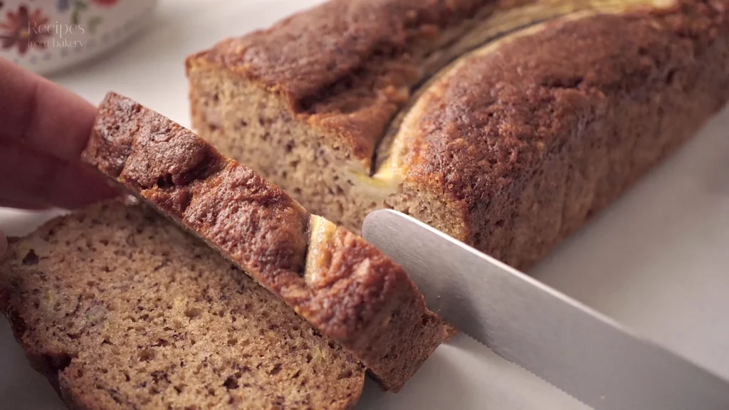 Cake à la banane moelleux, tranché sur une planche blanche.