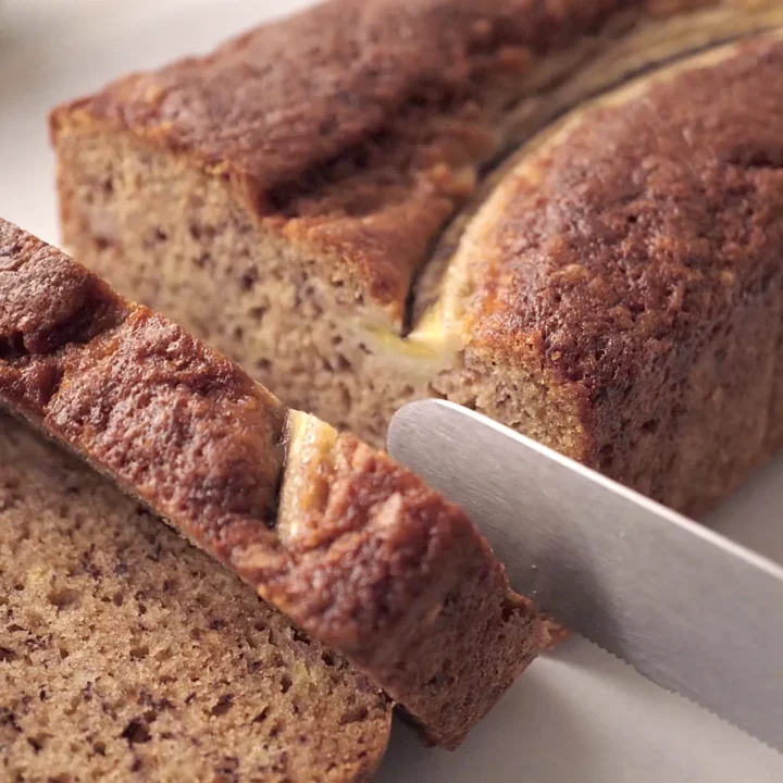 Cake à la banane moelleux, tranché sur une planche blanche.