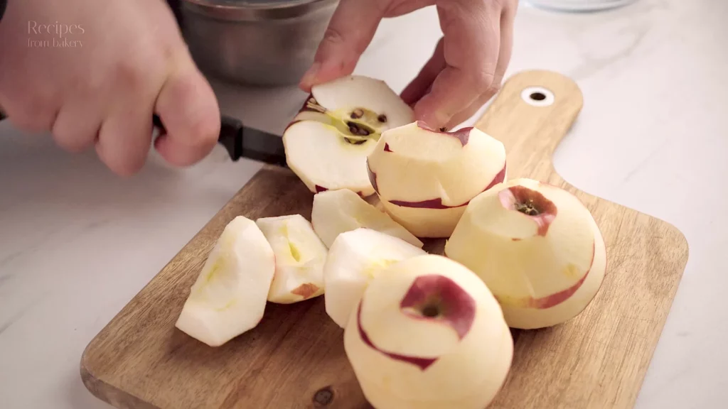 Pommes pelées et évidées sur une planche à découper avec les ingrédients autour