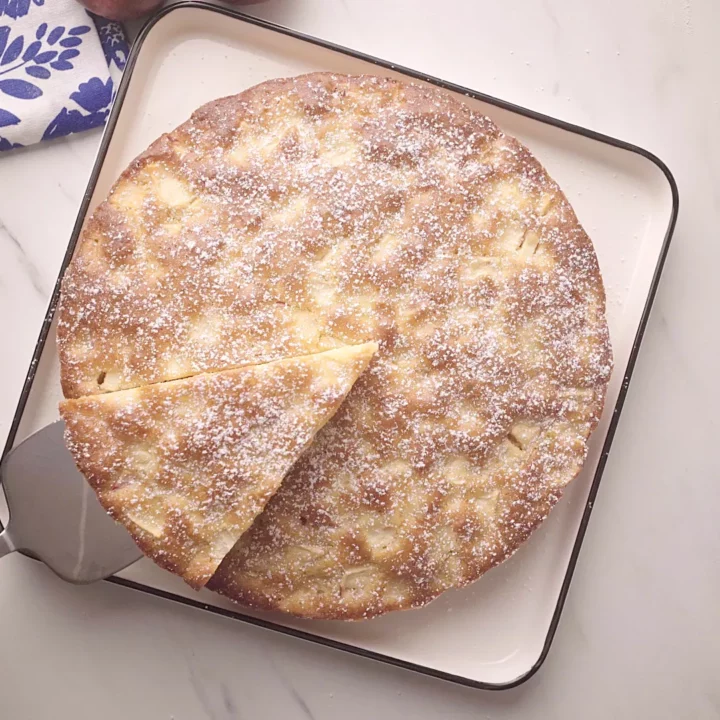 Gâteau aux pommes entier sur une assiette, avec une part retirée