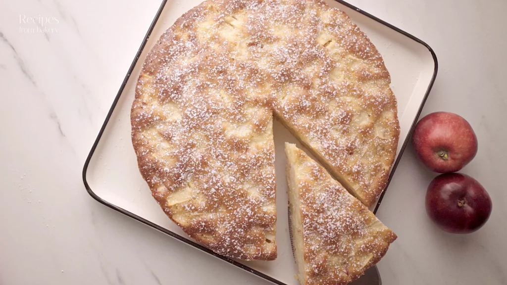 Gâteau aux pommes entier sur une assiette, avec une part prête à être servie