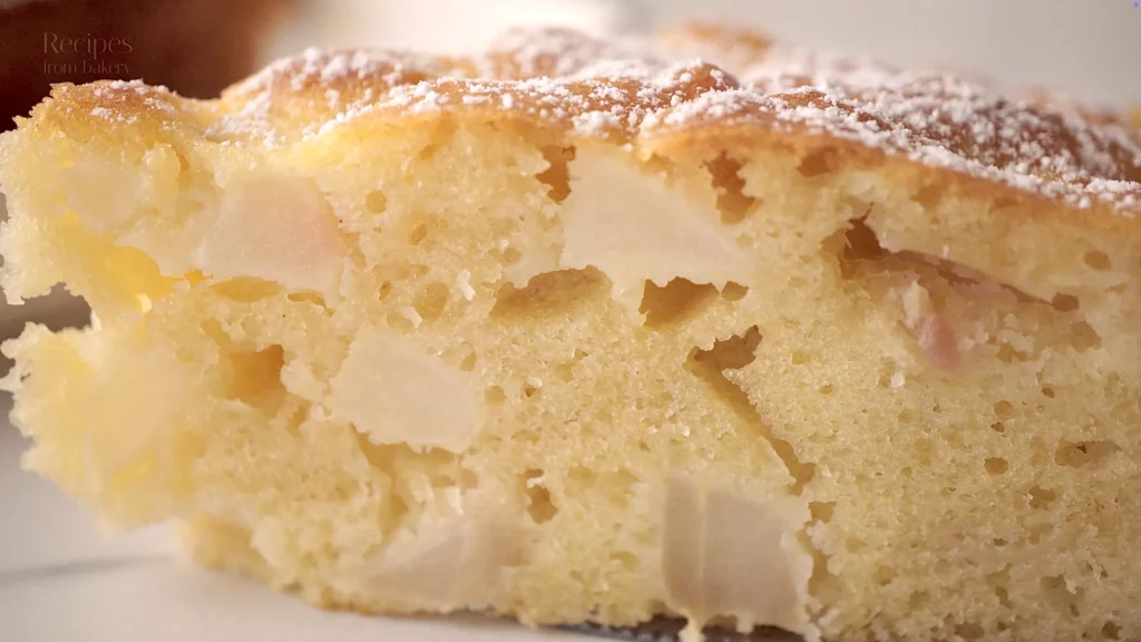 Gros plan sur la mie du gâteau aux pommes, avec morceaux de pomme visibles
