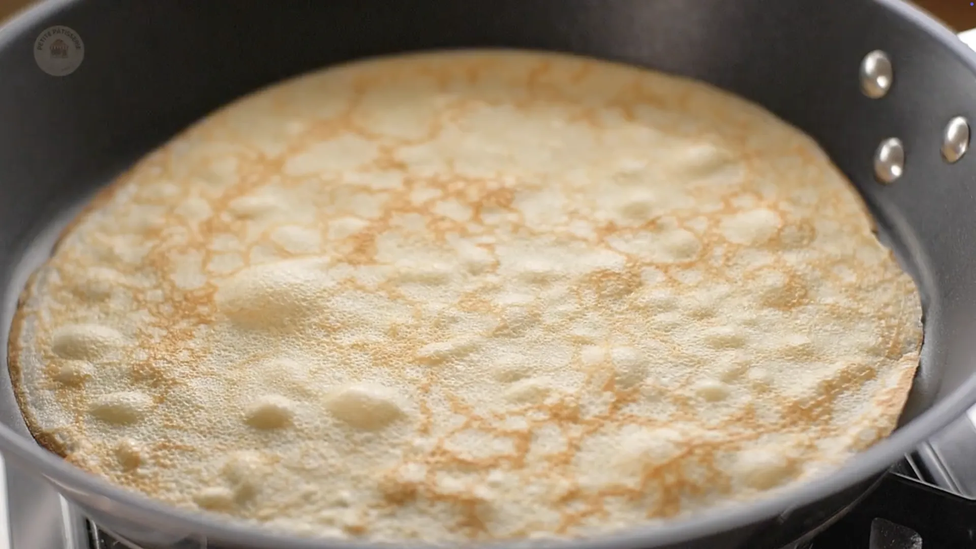 Crêpe fine en train de cuire dans une poêle chaude