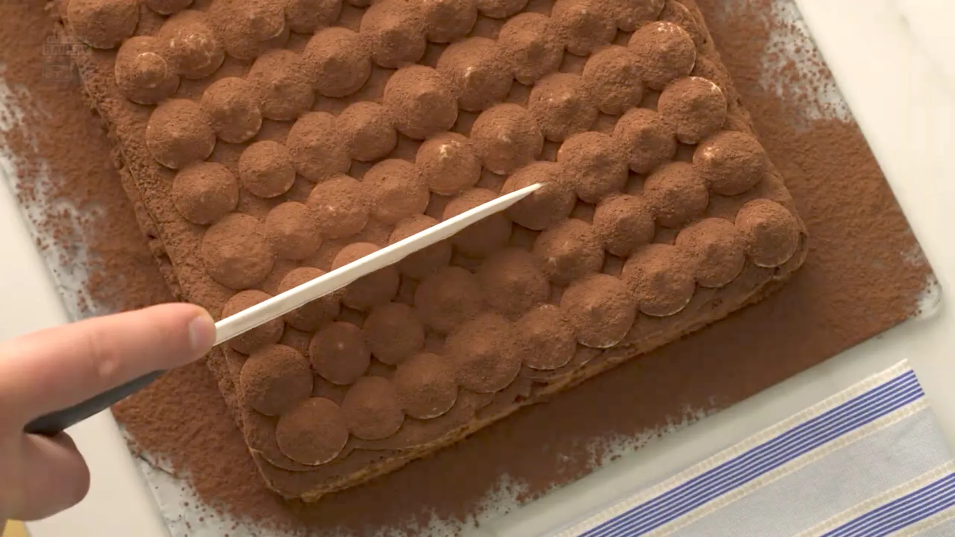 Tiramisu entier avant découpe, décoré de petites pointes de crème