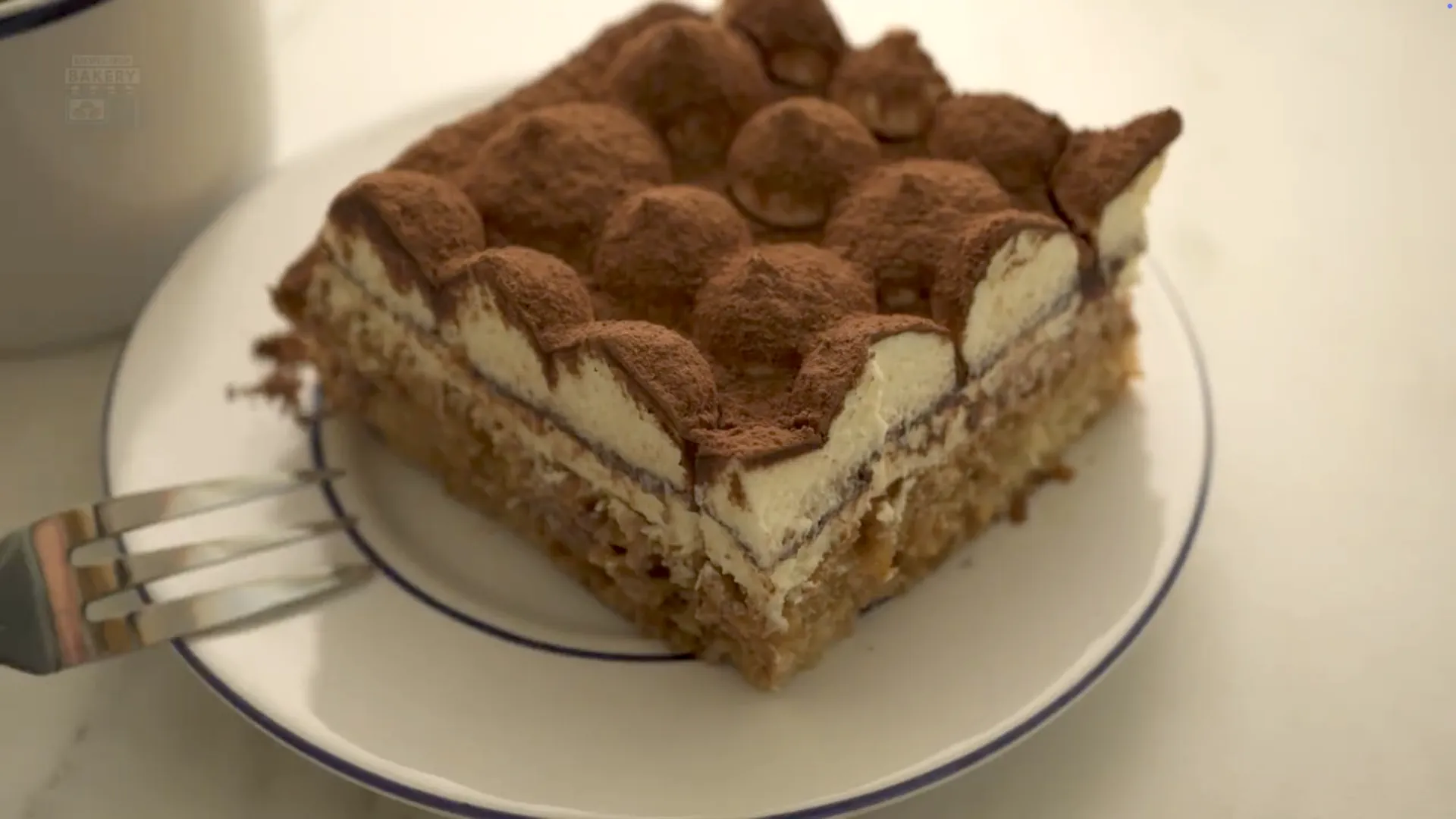 Portion de tiramisu servie sur une assiette blanche avec une fourchette